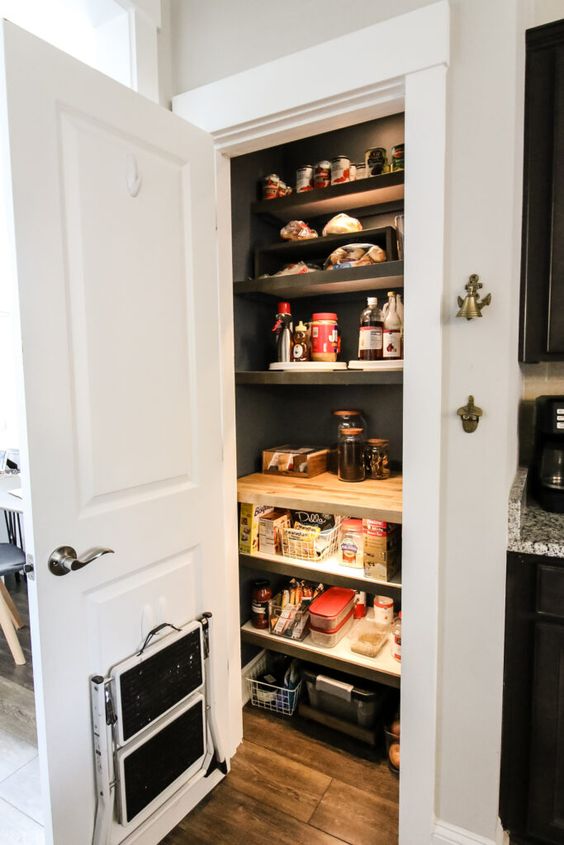 a small pantry with open shelves and built-in lights, metal wire baskets and various food and drinks is a lovely solution