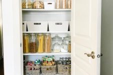 a small pantry with open shelves, cubbies, wire baskets, jars and containers and a door that hides it all away