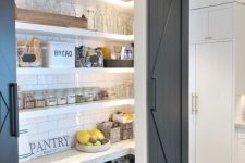 a small rustic pantry with built-in cabinets, a subway tile backsplash and open shelves, lights and various food and drinks