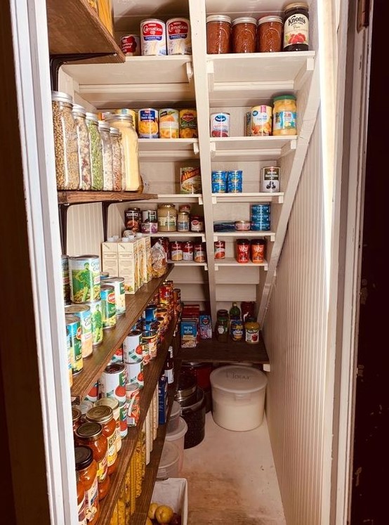 a small under stairs pantry with open shelves on the wall and built right into the staircase, with lights for more comfrotable using