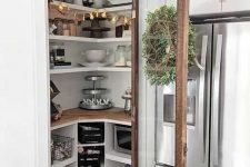 a small well-organized pantry with corner shelves and built-in open storage units, with lights and some tableware