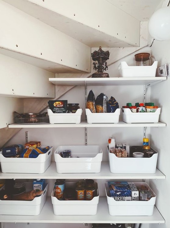 A small yet well organized under stairs pantry with open shelves and plastic cubbies is a cool solution to save your space
