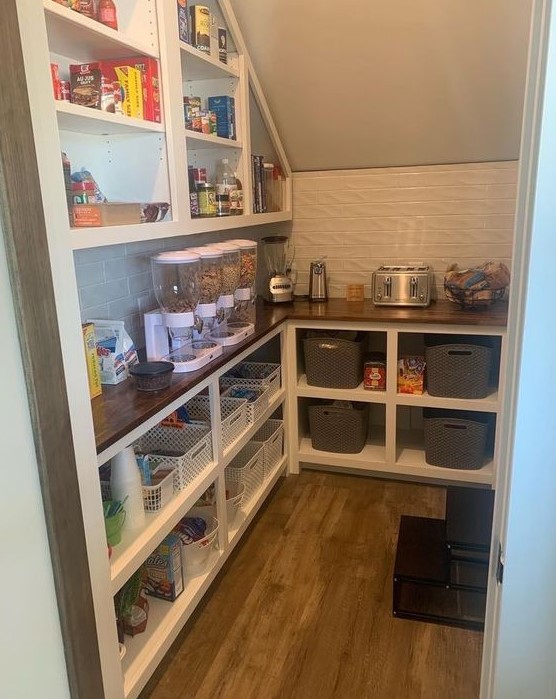 A smart staircase pantry with a built in storage unit with shelves and more shelves over it, with cubbies and all the necessary stuff here