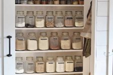 a smartly organized pantry with open shelves, cubbies, lots of jars to store all the food you want, a sliding door