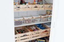 a smartly organized under stairs pantry with open shelves, wooden boxes, plastic containers and glass vessels