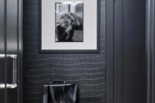 a soot entryway with reptile print wallpaper, a black pouf, an artwork and some cabinetry is very chic and refined