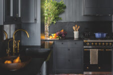 a soot farmhouse kitchen with smooth cabinets, ribbed shiplap walls and black stone countertops plus a backsplash