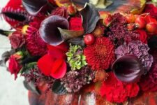 a sophisticated black Halloween pumpkin done with red, burgundy, deep purple blooms, foliage and berries