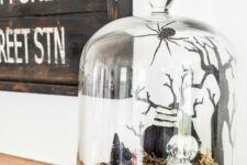 a spooky Halloween terrarium with hay, a skeleton, some trees, a spider and some other stuff is a bold and catchy idea