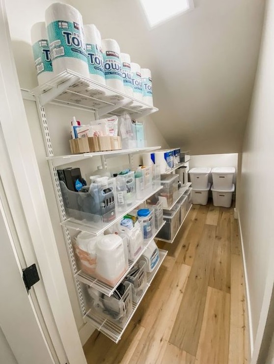 a staircase pantry with open shelving and some cubbies with lids plus lights is a cool and smart idea for any home