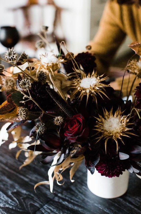 a statement Halloween floral arrangement with deep burgundy roses, dried blooms and leaves looks wow