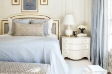 a subtle vintage bedroom with creamy walls, a neutral bed with blue and white bedding, creamy nightstands and a printed rug