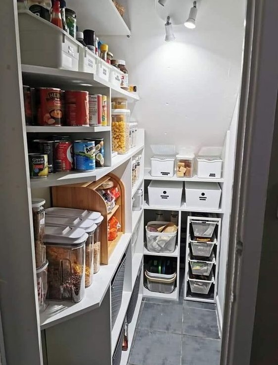 a tiny and cool staircase pantry with built-in shelves, plastic containers and cubbies, spotlights for comfortable using
