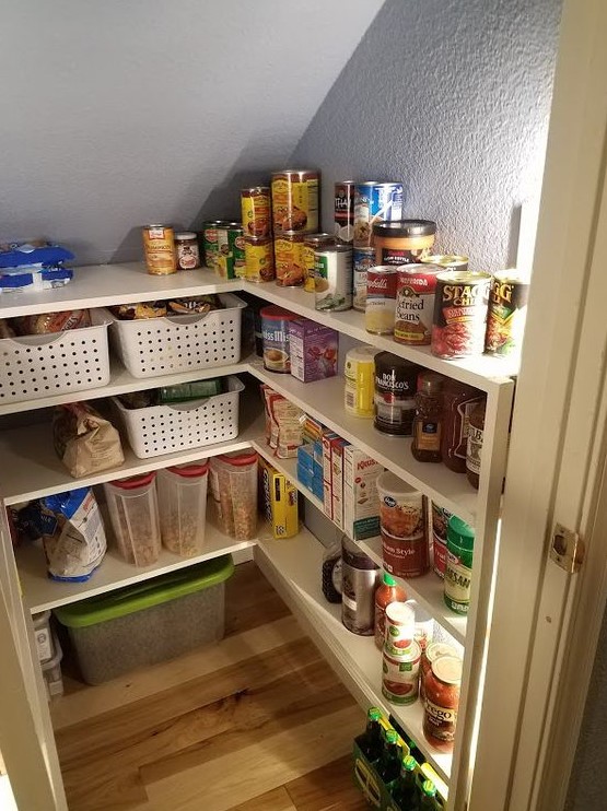 A tiny and well organized pantry with a built in shelving unit, plastic crates, additional light is a super smart idea