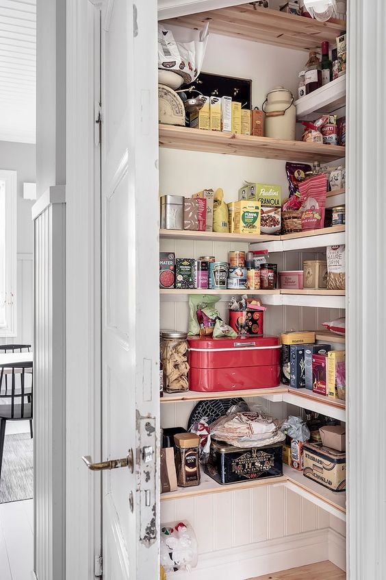 a tiny pantry with corner shelves, cookware and door is a smart solution to keep your space decluttered