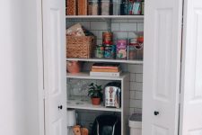 a tiny pantry with open shelves, a subway tile backsplash, cubbies and baskets for storage and some appliances and food