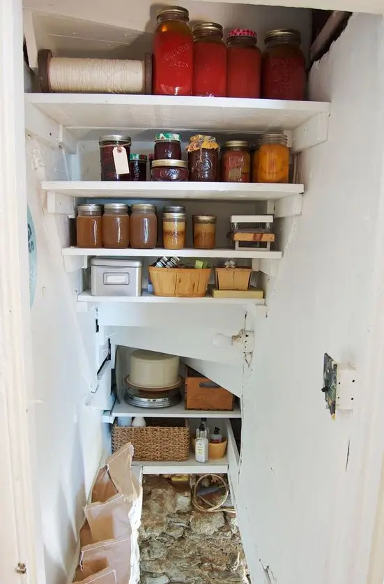a tiny under stairs pantry with built-in shelves, baskets, crates and food and drinks stored is a cool idea