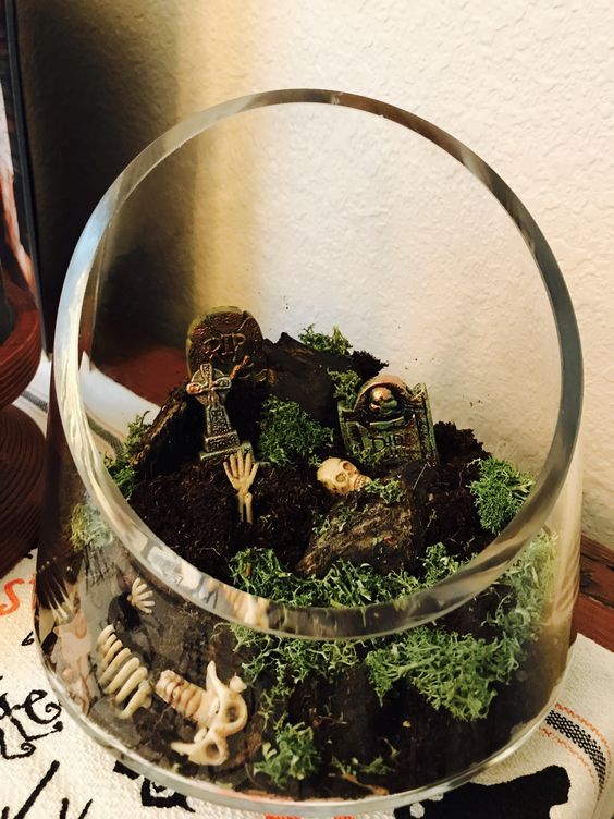 a very easy to make and fast Halloween terrarium with moss, skulls, bones and tombstones is a cool idea
