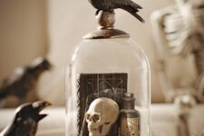 a vintage Halloween cloche with books, a skull, a poison bottle and a blackbird on top is a cool decoration to make yourself