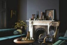 a vintage soot living room with a fireplace, a green sofa and green chairs, a rattan chair, a coffee table and somevases