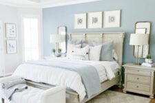 a welcoming bedroom with a pastel accent wall, a bed with blue and white bedding, a white upholstered bench, stained nightstands