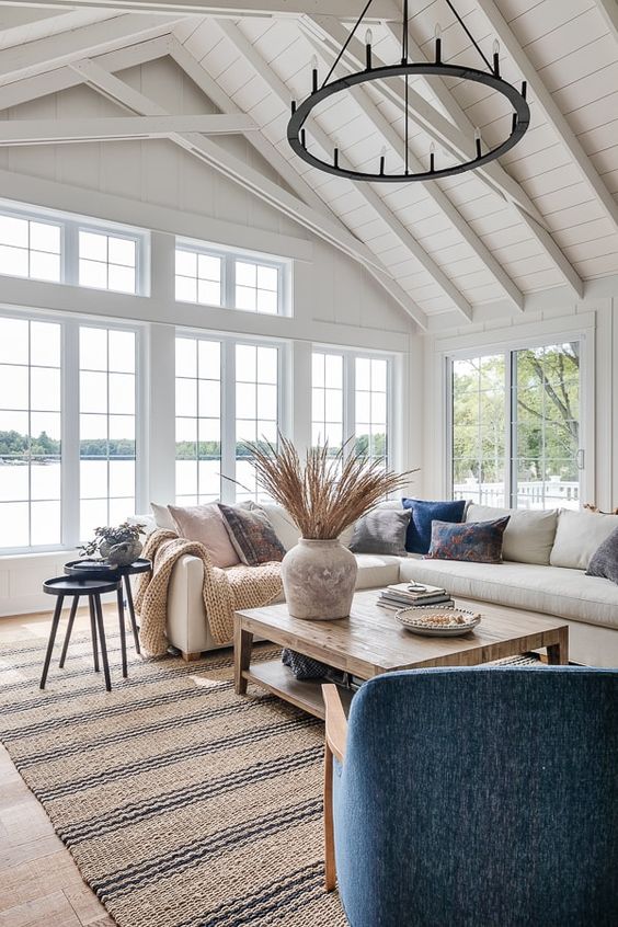 a welcoming coastal living room with a creamy sectional, a wooden coffee table, a blue chair, printed pillows, black side tables