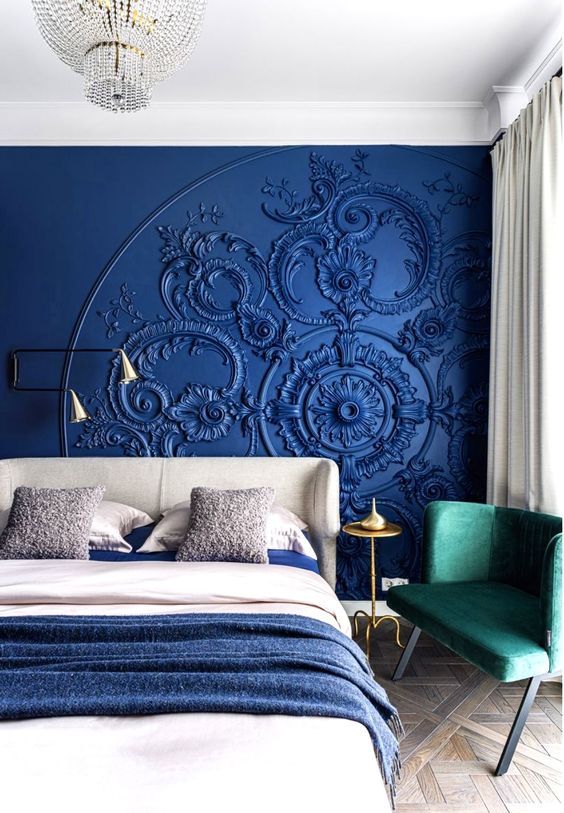 a whimsical bedroom with blue art on the wall, a grey bed with blue and neutral bedding, a green loveseat
