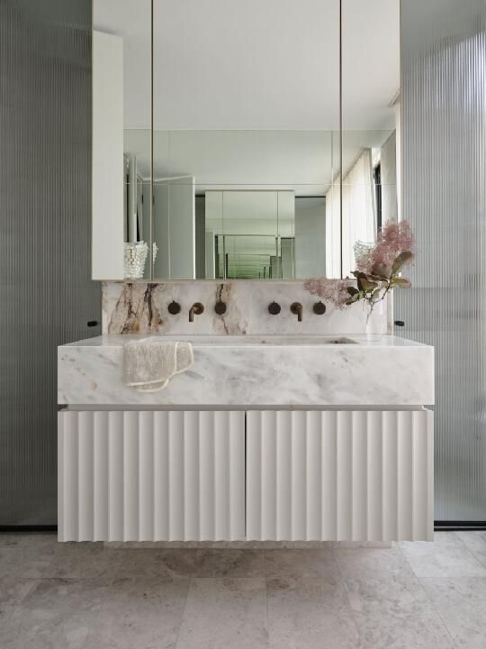 a white fluted floating vanity with a stone slab countertop and a large mirror is a cool solution for a neutral and refined bathroom