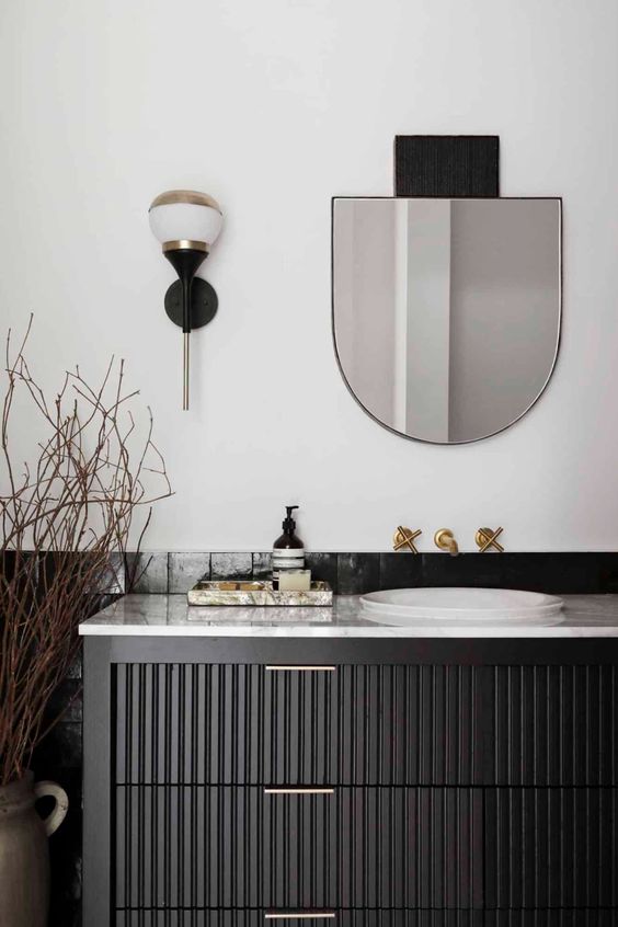 an elegant bathroom with a black reeded vanity, sinks, arched mirrors, branches, sconces is lovely