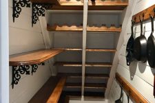 an elegant under the stairs pantry with stained shelves, a wine cellar, some pans hanging on the walls