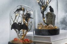 black Halloween cloches with moss, pumpkins, skulls, branches, bats, blackbirds and a tombstone plus lights