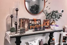 a Halloween console table with bats, vintage books and signs and other decor is a cool idea for styling a space