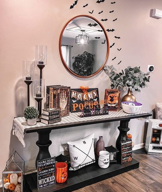 a Halloween console table with bats, vintage books and signs and other decor is a cool idea for styling a space