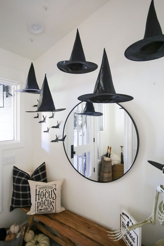 a Harry Potter entryway with witches' hats, a round mirror, a bench with pillows, a skeleton and some bats on the wall