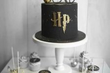 a Harry Potter sweets table with cupcakes, cake pops shaped as Snithces, a black and gold cake with glasses and a Snitch