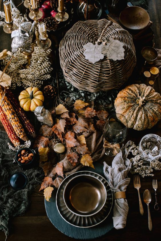 a Harry Potter themed tablescape with dark leaves, faux and natural pumpkins, a vine one, some dark porcelain and an owl
