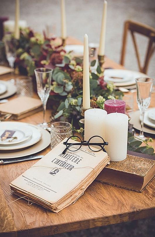 a Harry Potter themed tablescape with greenery, neutral and burgundy candles, books and eyeglasses