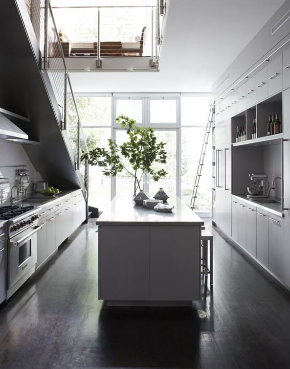 a Scandinavian kitchen with white cabinets, one part of it is placed under the stairs, with a large kitchen island and lots of natural light