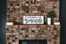 a beautiful rustic modern red brick fireplace with a matching mantel, greenery, mugs and vases and a crate with magazines