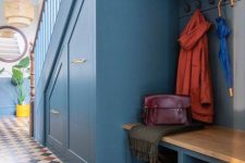 a blue under stairs mudroom with built-in drawers, a built-in bench and a cabinet, a pallet and some lights