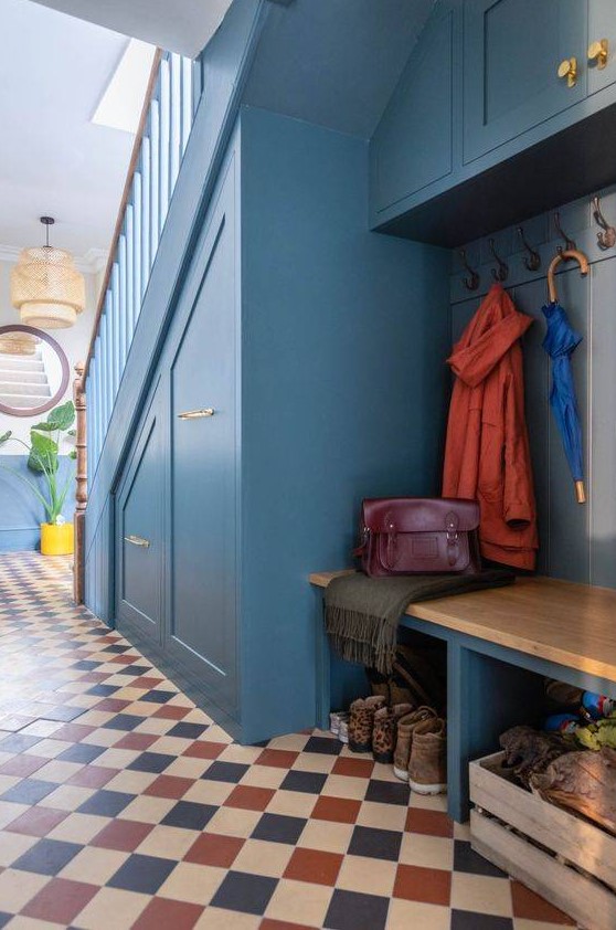 A blue under stairs mudroom with built in drawers, a built in bench and a cabinet, a pallet and some lights