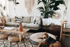 a boho chic living room with a printed rug and pillows, a macrame hanging, potted plants and jute ottomans