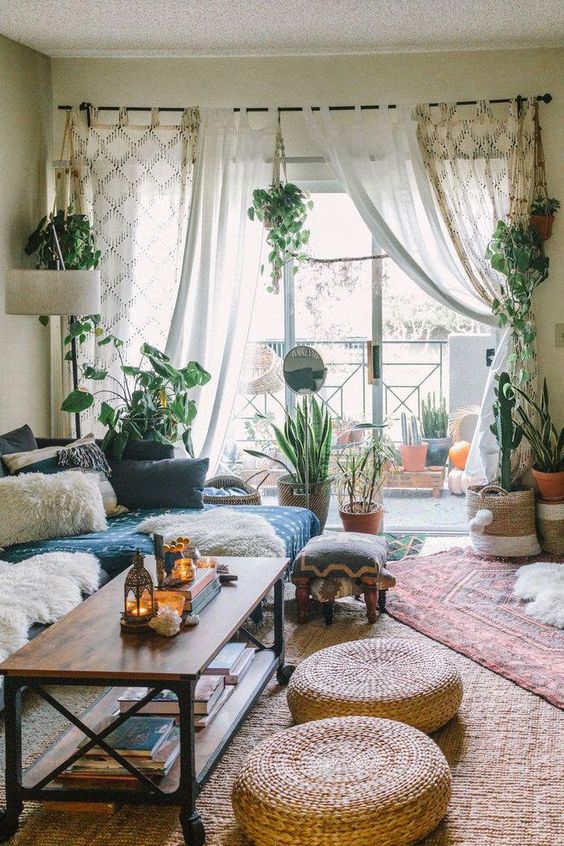 a boho living room with a blue sectional, printed pillows, a coffee table, jute cushions, potted plants