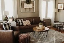a boho rustic living room with brown leather seating furniture, a hairpin leg table, a brown leather pouf, some shabby chic decor