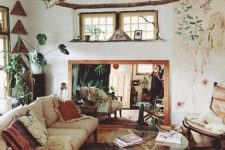 a boho space with boho rugs and pillows, branch hangings, a mirror, a glass coffee table and potted plants