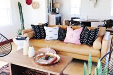 a bright and catchy boho living room with an amber sofa and printed pillows, a coffee table and a boho rug and potted plants