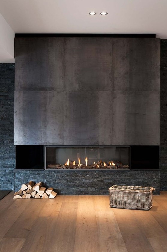 a built-in fireplace with darkened steel sheets over it and faux stone under it feels very woodland-like and cool