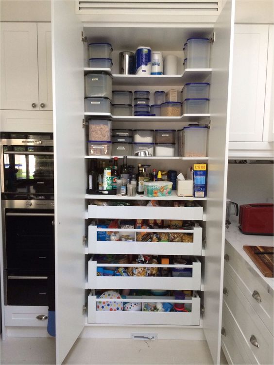 A built in pantry organized right to store as much as possible, with shelves and drawers, containers, jars and various types of food