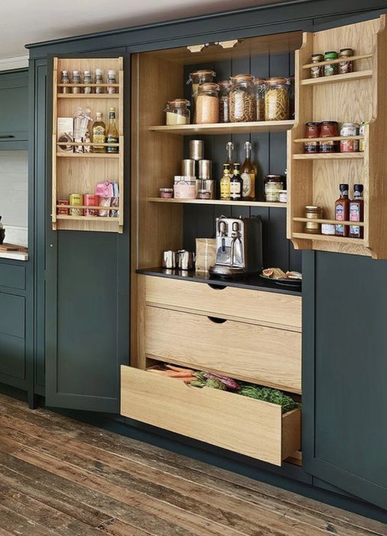 A built in pantry with dark green panels and backing, stained shelves, drawers and shelves on the doors is a smart solution