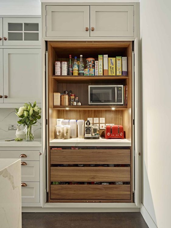 A built in pantry with open shelves and LED lights, drawers, some food, appliances and spices and oils